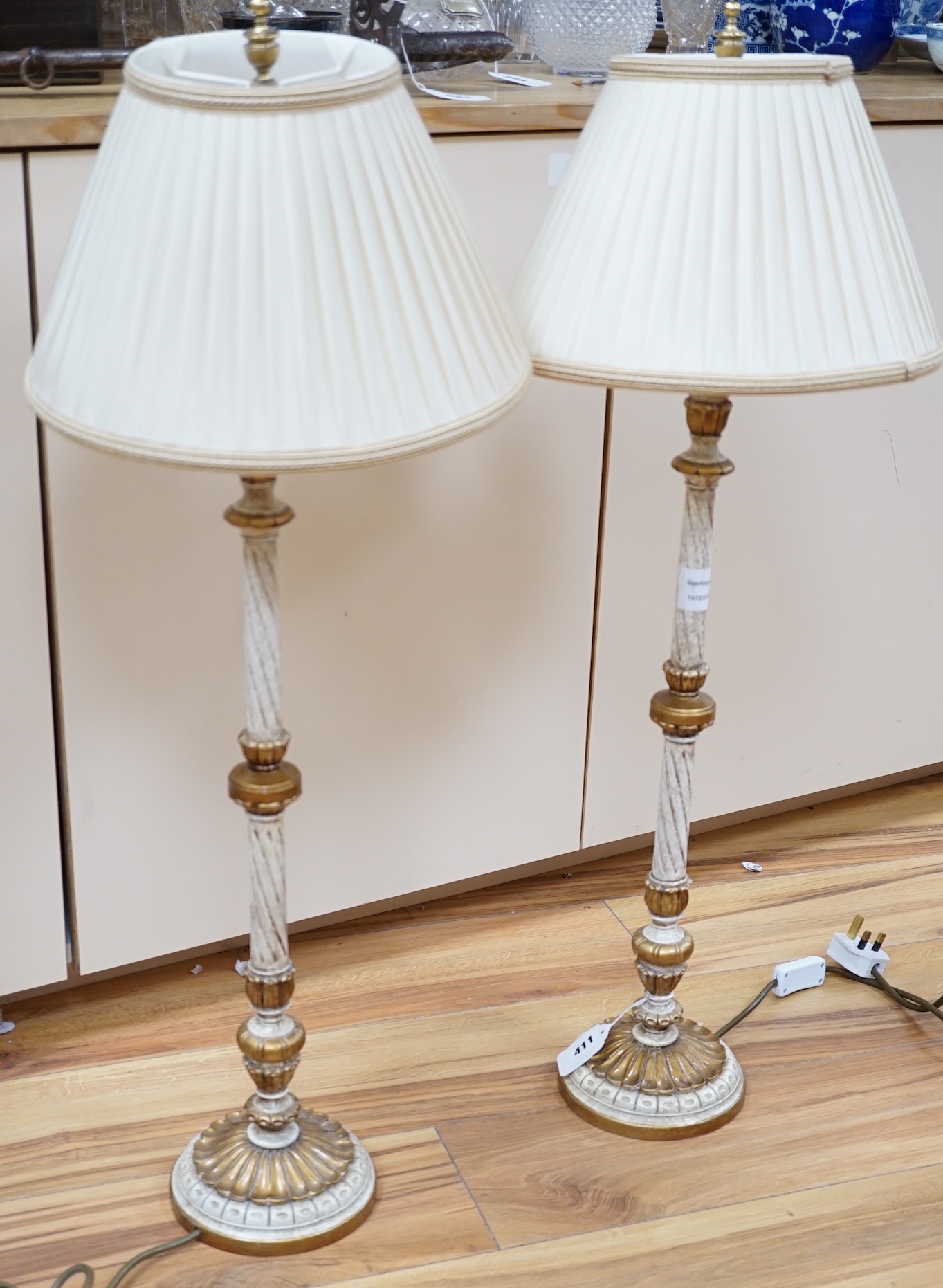 A pair of gilt and cream painted lamps, 83cm high